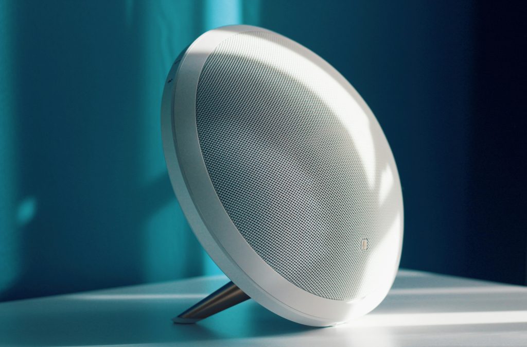 Close-up of a modern wireless speaker with a minimalist design, lit by natural light indoors. Ideal for tech product showcase.